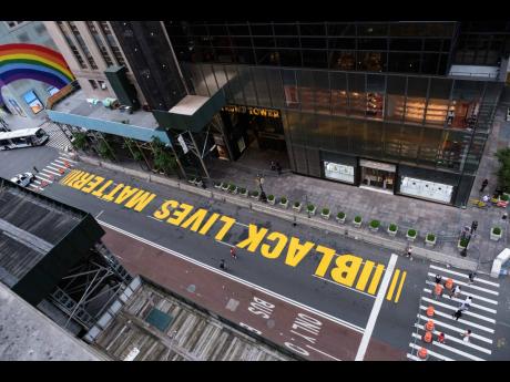 Pedestrians walk on a Black Lives Matter mural painted in front of Trump Tower, Friday, July 10, 2020, in New York. 