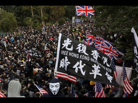 In this January 2020 file photo, participants wave British and US flags during a rally demanding electoral democracy and call for boycott of the Chinese Communist Party and all businesses seen to support it in Hong Kong.   