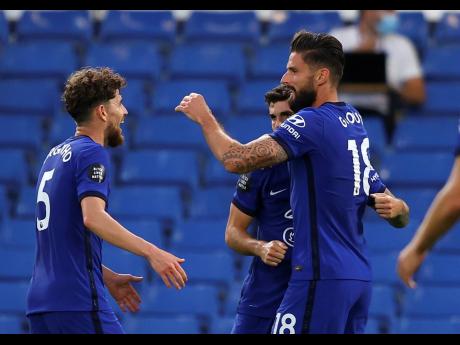 Chelsea’s Olivier Giroud (right) is congratulated by teammates after scoring his team’s first goal during the English Premier League match between Chelsea and Norwich City at Stamford Bridge in London, England, yesterday. Chelsea won 1-0.