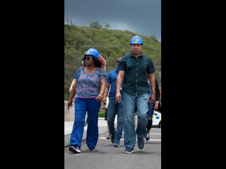 Permanent Secretary Audrey Sewell walks alongside Prime Minister Andrew Holness during a tour of an overpass on Mandela Highway on Sunday, July 21, 2019. 