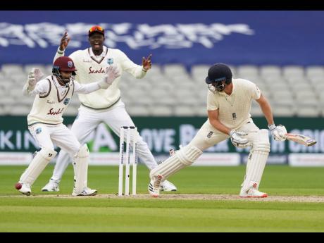 ABOVE: Windies’ wicketkeeper Shane Dowrich (left) and captain Jason Holder (center) appeal unsuccessfully for the wicket of England’s Dom Sibley during the first day of the second cricket Test match at Old Trafford in Manchester, England yesterday.