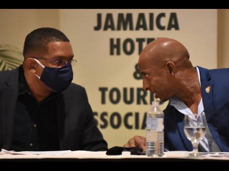 Omar Robinson (right), president of the Jamaica Hotel and Tourist Association (JHTA), and Wayne Cummings, past president, consult during a press conference at The Jamaica Pegasus hotel on Tuesday.