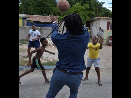 Alando Terrelonge playing street basketball with children in Gregory Park, Portmore, in his St Catherine East Central constituency last Saturday.