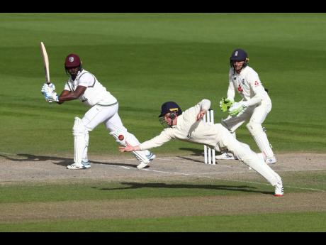 England’s Ollie Pope (centre) dives to take the catch to dismiss Windies’ Kemar Roach (left) during the last day of their second Test match at Old Trafford in Manchester, England on Monday.