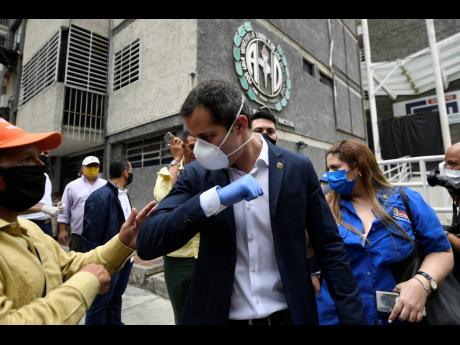 In this June 17 photo, Venezuelan opposition leader Juan Guiado greets a supporter after a visit to the headquarters of Democratic Action political party in Caracas, Venezuela, the day after Venezuela's Supreme Court ordered its takeover ahead of parliamen
