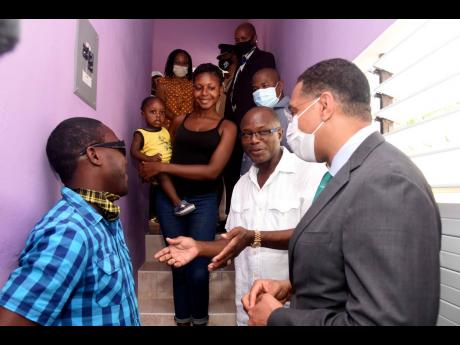 Prime Minister Andrew Holness (right) dialogues with Kemoy Thomas (left) and St Catherine South West Member of Parliament Everald Warmington (second right) and other members of the community after a newly built home was handed over to Thomas, who is visual