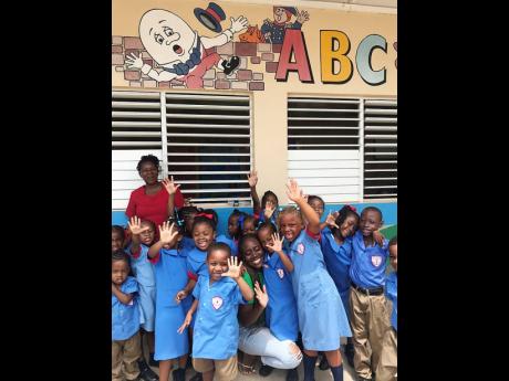 Brittania Gordon, public relations officer for the Fi We Children Foundation, is surrounded by students of Laura’s Basic School, recipients of the organisation’s first back-to-school drive in 2019.