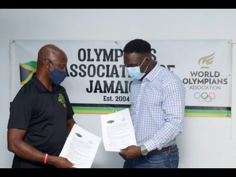 
Irwine Clare (left), founder and CEO of Team Jamaica Bickle, and Marvin Anderson, president of the Olympians Association of Jamaica, show off the documents after signing a memorandum of understanding at the National Stadium on Friday.