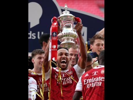 
Arsenal’s Pierre-Emerick Aubameyang lifts the trophy during the presentation for the FA Cup final match between Arsenal and Chelsea at Wembley stadium in London, England, yesterday. Arsenal won the match 2-1.