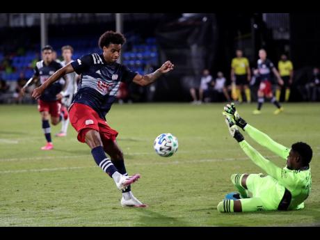Philadelphia Union goalkeeper Andre Blake (right) makes a save as New England Revolution forward Tajon Buchanan shoots on goal during the first half of an MLS match in Kissimmee, Florida, on Saturday, July 25.