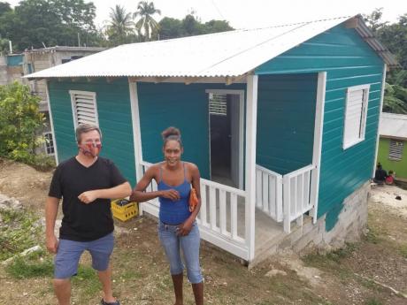 Carl Robanske, executive director of Embracing Orphans, elbow bumps Simone Gordon while they stand in front of her recently built house in Tower Hill, St James. 