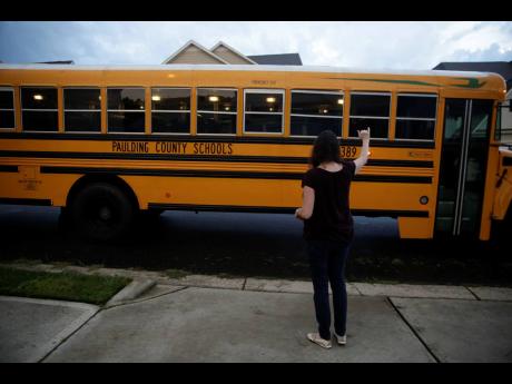 Rachel Adamus waves goodbye to her two children, Paul and Neva, as they ride the bus for the first day of school yesterday in Dallas, Georgia. 