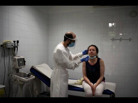 In this July 31, 2020 file photo, Emma Gaya is tested for COVID-19 at a primary healthcare centre in Sant Sadurní d’Anoia, Catalonia region, Spain. 