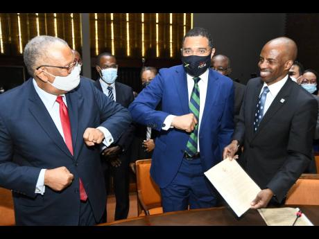 Prime Minister Andrew Holness (centre) and Leader of the Opposition, Dr Peter Phillips, knock elbows COVID style after the signing of a memorandum of understanding between key stakeholders of a National Consensus on Crime at the Jamaica Conference Centre i