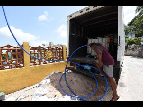 A man pumps water from a truck to a house in Pigeon Valley in West Rural St Andrew. Residents have complained that they have not had any water in their pipes for up to six months and have had to be buying water.