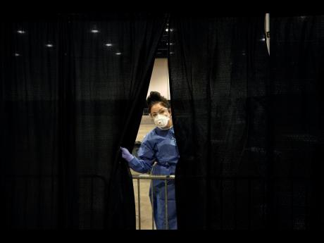 Diana Vega, a registered respiratory therapist, peeks through a curtain during setup at a temporary coronavirus testing site on Monday.