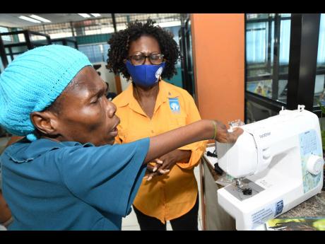 Daphne Williams (left) pronounces a blessing on her sewing machine after Claudette Christie, group marketing and communications manager of the Jamaica Co-operative Credit Union League, presented the donation in May Pen, Clarendon, on Wednesday. The 51-year