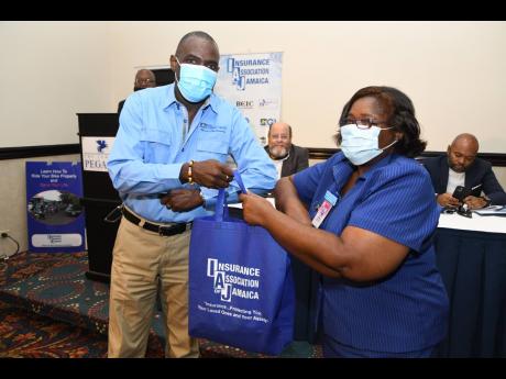 Carmen Brissett, first vice-president, Nurses Association of Jamaica, accepts 1,000 masks from Oliver Tomlinson, general manager, JN Life and Insurance Association of Jamaica’s vice- president.