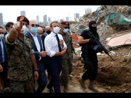 French President Emmanuel Macron (centre) visits the devastated site of the explosion at the port of Beirut, Lebanon, on Thursday. His visit to  Beirut is to offer French support to Lebanon after the deadly port blast.