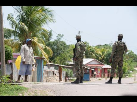 Members of the Jamaica Defence Force speak with a resident as he attempts to enter the quarantined zone in Sandy Bay, Clarendon, on Thursday, August 6. Residents of the community awoke to a 14-day COVID-19 lockdown.