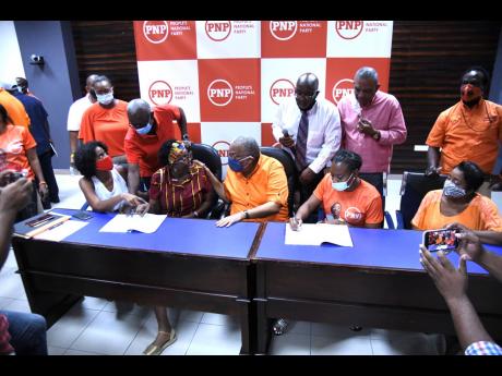 People’s National Party President Dr Peter Phillips (seated, centre) speaks with prospective election candidate Dr Angela Brown Burke as Krystal Tomlinson signs the covenant and declaration against corruption at The University of the West Indies, Mona, y