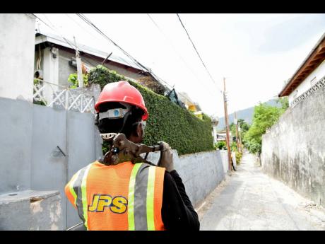 A Jamaica Public Service Company worker prepares to install a new system for residents of Standpipe, St Andrew, on Monday to access electricity supply legally.