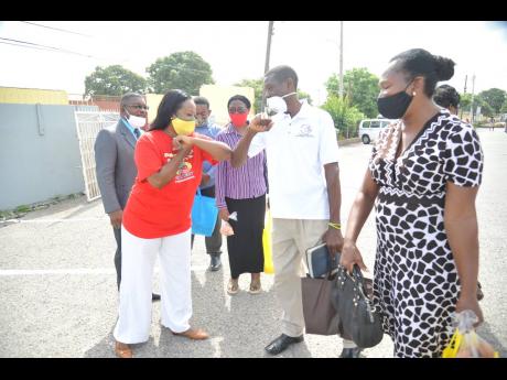 Yodit Getachew-Hylton, honorary counsul for Ethiopia in Jamaica, bumps elbows with a member of the Waltam Park New Testament Church of God, while other members of her team look on. The consulate has donated more than 1,000 care packages to churches and hom
