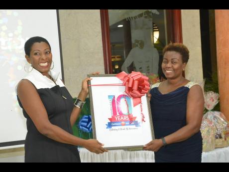 Debra Frazer (left), chief executive officer at Caribbean HR Solutions, presents Caribbean HR Solutions 10-year memento to Gloria Henry, president of the Global Services Association of Jamaica. 