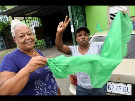 Elizabeth Reid (left) and Normalyn Wallace, JLP supporters, display their political colours in Olympic Gardens on Monday, August 17. They credit Andrew Holness for cementing Jamaica Labour Party dominance in the St Andrew West Central.