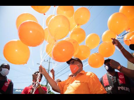 Dr Peter Phillips, People’s National Party president and incumbent for St Andrew East Central, releases confetti-filled orange balloons outside Tarrant Baptist Church following his successful nomination on Tuesday.