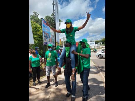 The JLP’s Rhoda Crawford rides on the shoulders of a supporter in Manchester Central on nomination day Tuesday.
