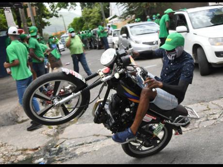 A Jamaica Labour Party (JLP) supporter performs stunts during a tour of Woodford Park by Kari Douglas, the party's candidate in St Andrew South Eastern, on Wednesday, August 19. Thirty-six per cent of respondents in an RJRGLEANER-Don Anderson poll would vo