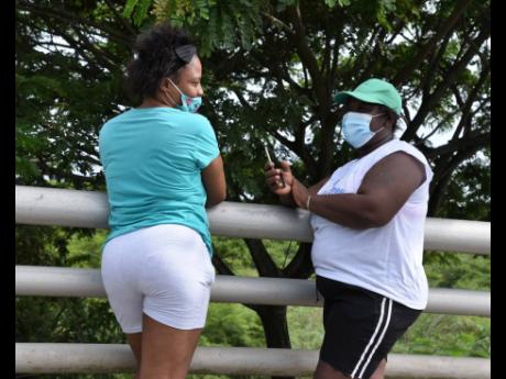 Left: Karen Smith (left) and her friend, Shelly Cameron (right), stop to chat on the Morant Bay bridge after delivering food packages to relatives living in Church Corner, St Thomas, which has been quarantined since August 6 because of an upsurge in corona