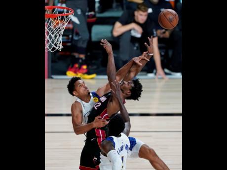 Miami Heat forward Jimmy Butler (centre) is fouled by Indiana Pacers guard Malcolm Brogdon (left) as he drives to the basket during the second half of an NBA basketball first round playoff game on Saturday, August 22, 2020, in Lake Buena Vista, Fla.
