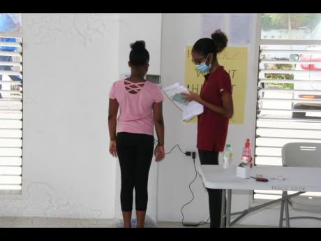 Third-year medical student at the UWI, Dominique Ramsingh (right), do weight checks on a Bethel Primary School student during the Hanover Charities’ back-to-school medical clinic, held in the Orchard Sports and Community Centre in Hopewell, Hanover, on S