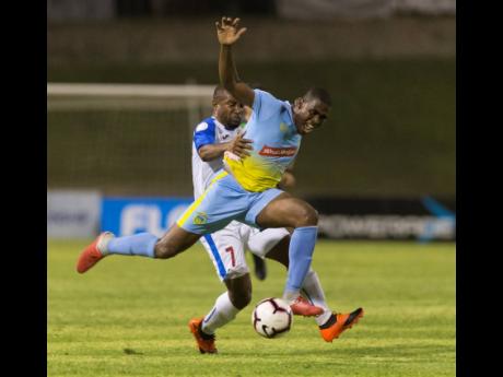 Waterhouse’s Keithy Simpson (foreground), on the receiving end of a tackle from Portmore United’s Damian Williams at Stadium East in the 2019 FLOW Concacaf Caribbean Club Championship on Thursday May 16, 2019.