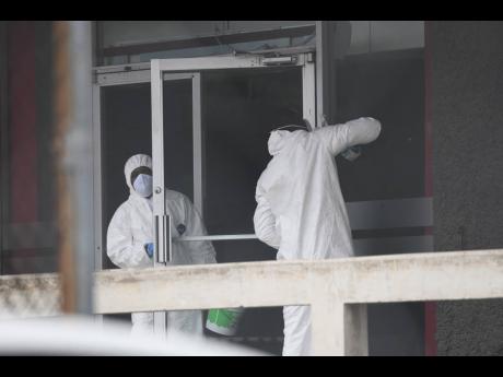 A sanitisation crew conducts cleaning of the Central Sorting Office building on April 17, 2020, amid the threat of coronavirus contagion from the commingling of staff at a call centre sited there. Janitorial companies are doing brisk business doing coronav