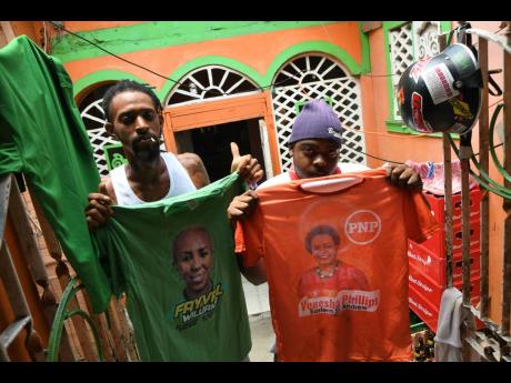 From left: Kemar Demon and Romario James, who live in the same house, show their political unity in colours at the Standpipe community in St Andrew Eastern. 
