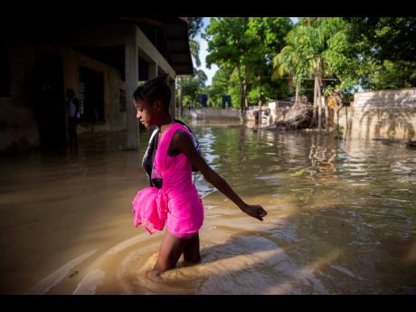 A girl wades towards her flooded home the day after the passing of Tropical Storm Laura in Port-au-Prince, Haiti, on Monday, August 24, 2020. Laura battered the Dominican Republic and Haiti on it's way to the US Gulf Coast, where it hit as a powerful Categ