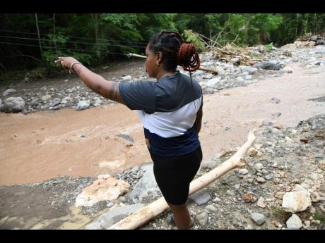 A resident shows the now-impassable road to Cane River, which was completely eroded by the river following heavy rains in the area, on Monday, August 24. 