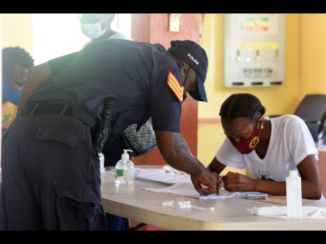 A policeman searches for his name on the voters’ list at the National Police College of Jamaica in Twickenham Park, St Catherine, on Monday. Election day workers and the security forces cast their ballots three days ahead of the September 3 poll.