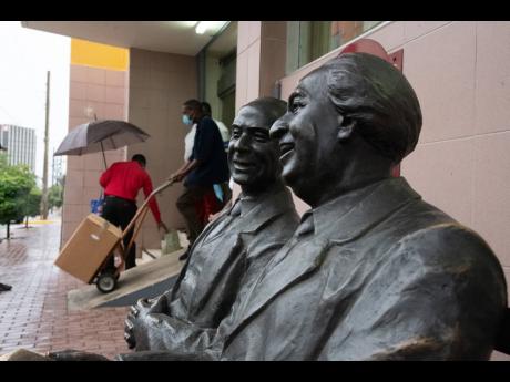 An Electoral Office of Jamaica worker wheels out supplies in the background of statues of the fathers of Jamaica’s Independence-era democracy, Alexander Bustamante and Norman Manley. Approximately 1.9 million voters are eligible to go to the polls today 
