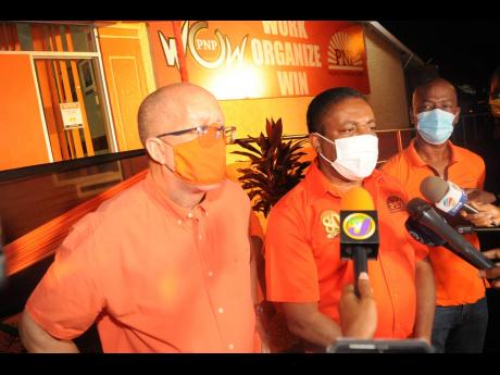 Phillip Paulwell (centre) speaks to the media at the People’s National Party headquarters after the party lost the general elections. 