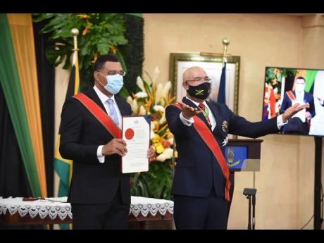 Governor General Sir Patrick Allen invites guests to stand after the presentation of the instrument of appointment to Prime Minister Andrew Holness at Monday’s swearing-in ceremony at King’s House. Four other ministers were later sworn in.