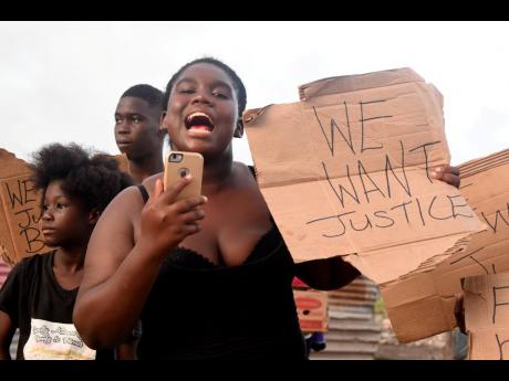A demonstrator protests the police shooting of a 22-year-old man in Old Harbour Bay, St Catherine, on Thursday. The circumstances of the day-earlier shooting are disputed. 