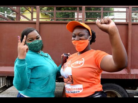 
These two women who support the Jamaica Labour Party and the People’s National Party, respectively, display their parties’ signs during the September 3 general election at Mannings Hill Primary School, 
St Andrew West Rural.