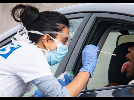 A medical worker takes a swab at a drive-in coronavirus testing facility in England.