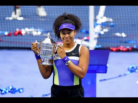 Naomi Osaka holds up the championship trophy after defeating Victoria Azarenka in the women’s singles final of the US Open tennis championships yesterday in New York.