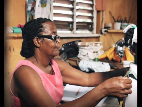 Elma Thompson, owner of Miss T’s Hardware in Granville, St James, fits a uniform on a young student from her community. Miss T makes uniforms for children and gives them away for free to struggling parents. She says the grant from the Supreme Heroes prog