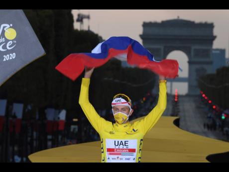 Tour de France winner, Slovenia’s Tadej Pogacar, celebrates his victory on the podium with a Slovenian flag, with the Champs-Elysees in the background in Paris, France, yesterday.